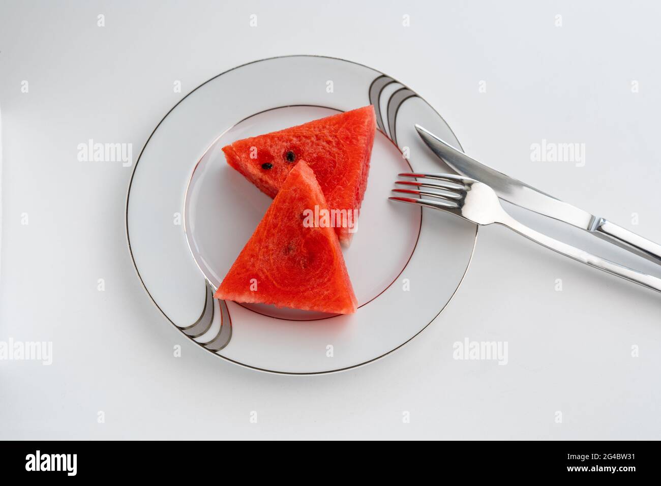 Due fette di cocomero su piatto bianco e sfondo bianco, stile elegante Foto Stock