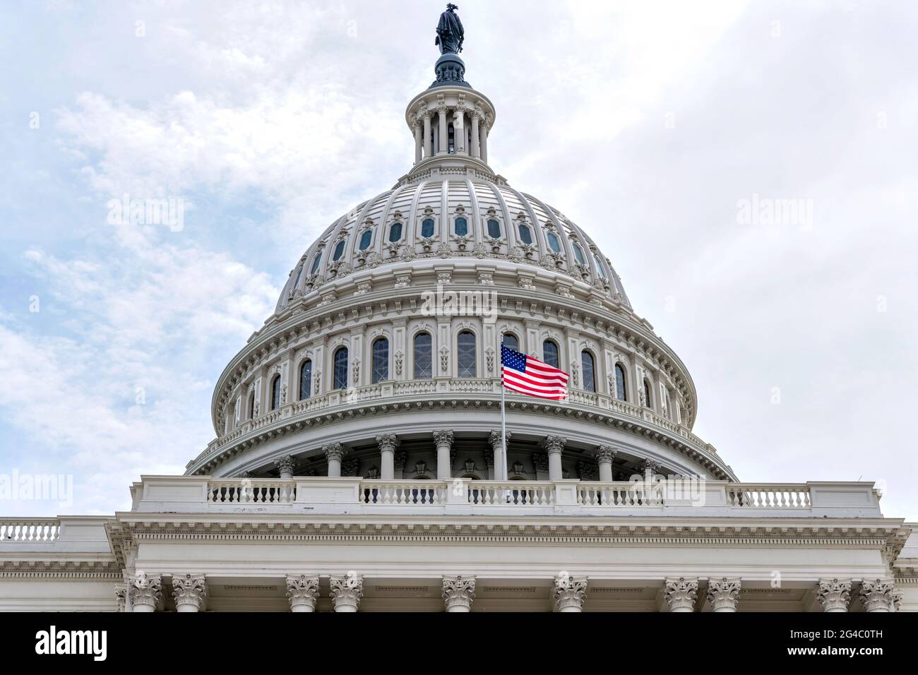 The Dome - una vista ravvicinata e bassa di una bandiera nazionale degli Stati Uniti che vola di fronte alla cupola del Capitol Building. Washington, D.C., Stati Uniti. Foto Stock