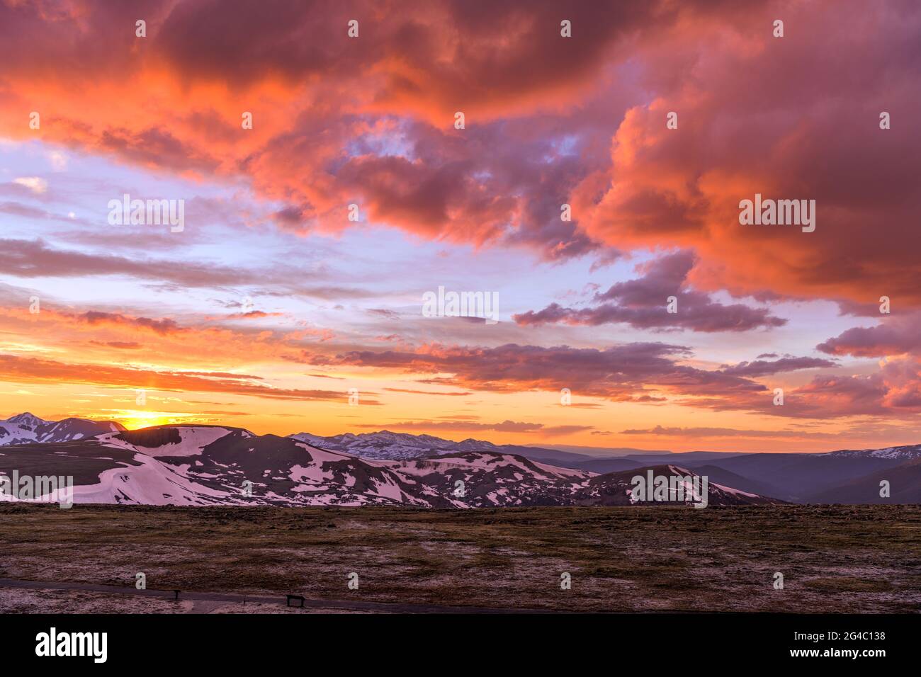 Tramonto primaverile alla cima delle Montagne Rocciose - una vista grandangolare delle colorate nuvole del tramonto primaverile sulle cime innevate del Continental divide, RMNP, CO. Foto Stock