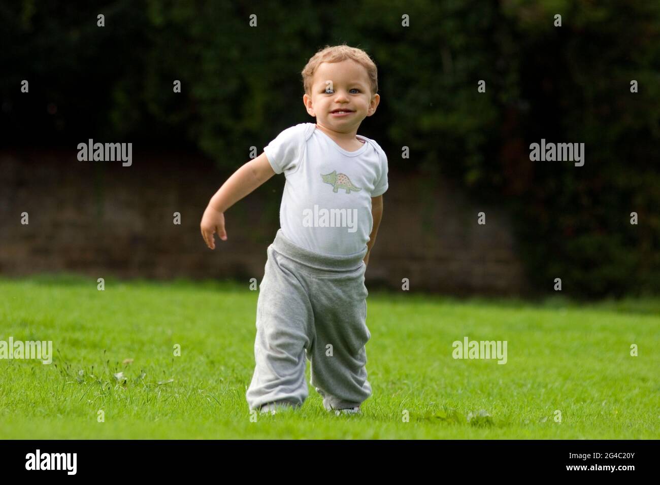 felice bambino piccolo che prende i suoi primi passi all'aperto Foto Stock