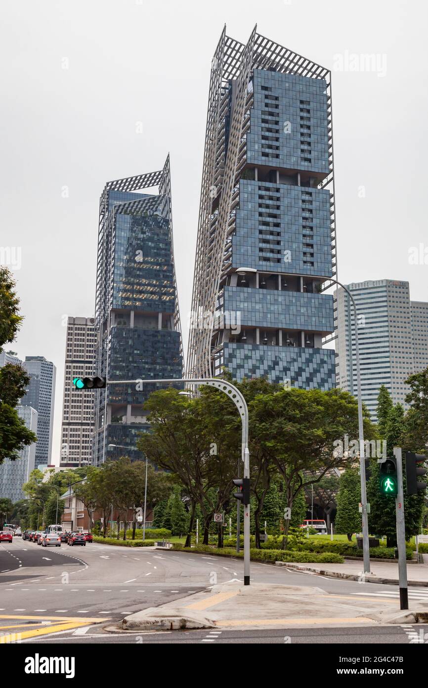 Edifici contemporanei nel centro cittadino di Singapore tra alberi con la Citta' Suntec sullo sfondo e un semaforo verde Foto Stock