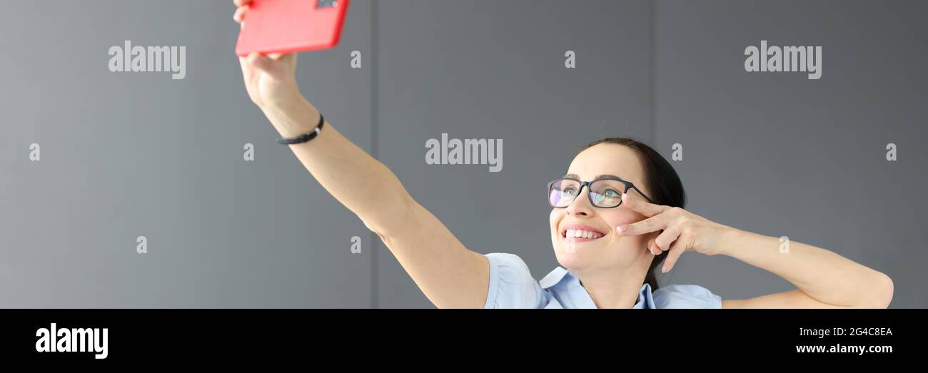 Donna con occhiali che sorridono e prendono selfie Foto Stock