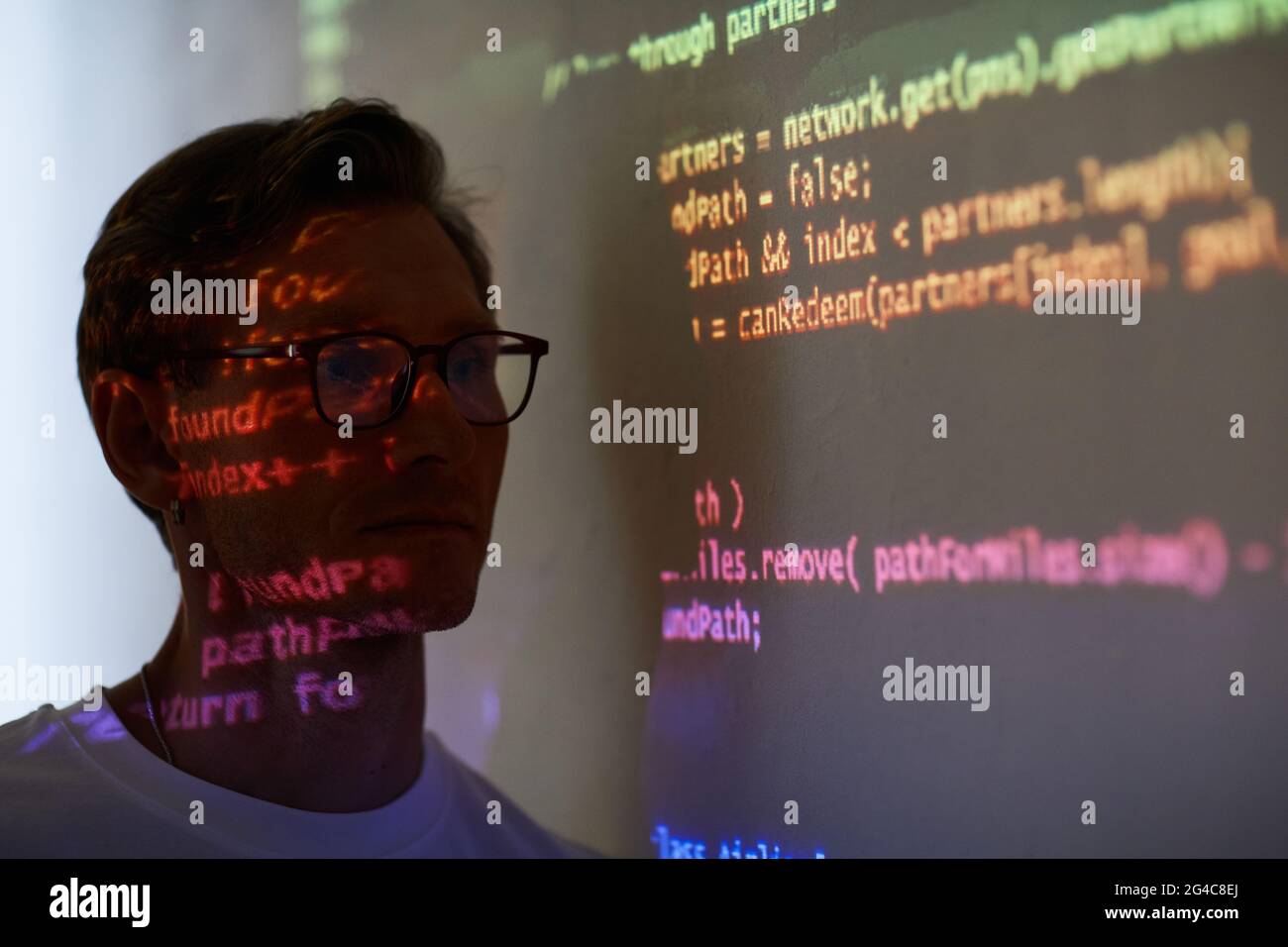 Giovane sviluppatore che legge il codice del computer sulla lavagna bianca durante la presentazione in camera oscura Foto Stock