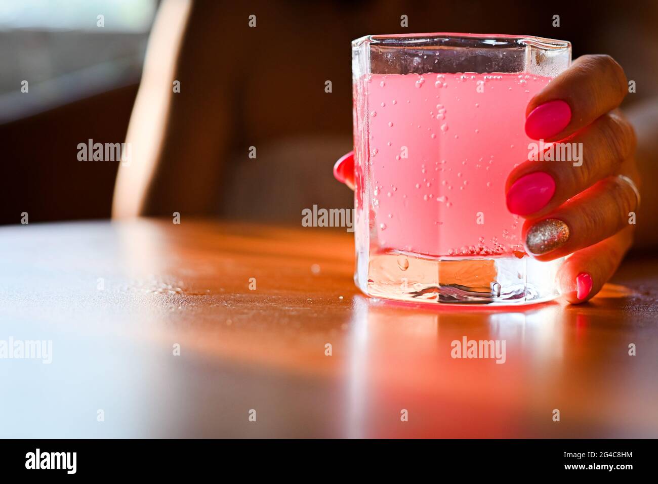 ragazza che tiene un bicchiere con un cocktail rosa Foto Stock