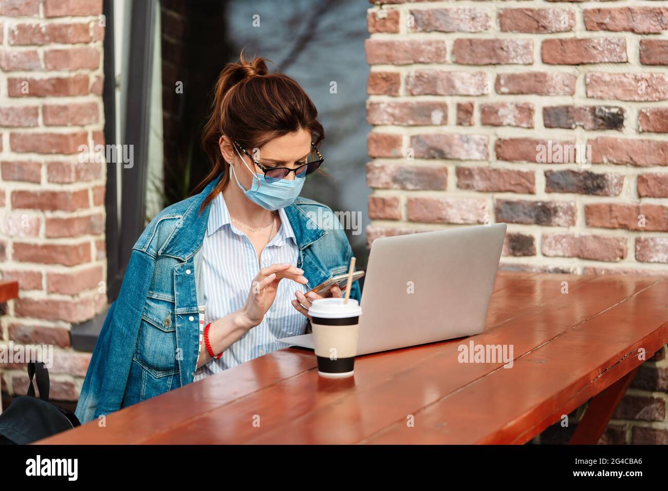Una giovane donna lavora a distanza su un laptop durante la pandemia del Covid-19 Foto Stock