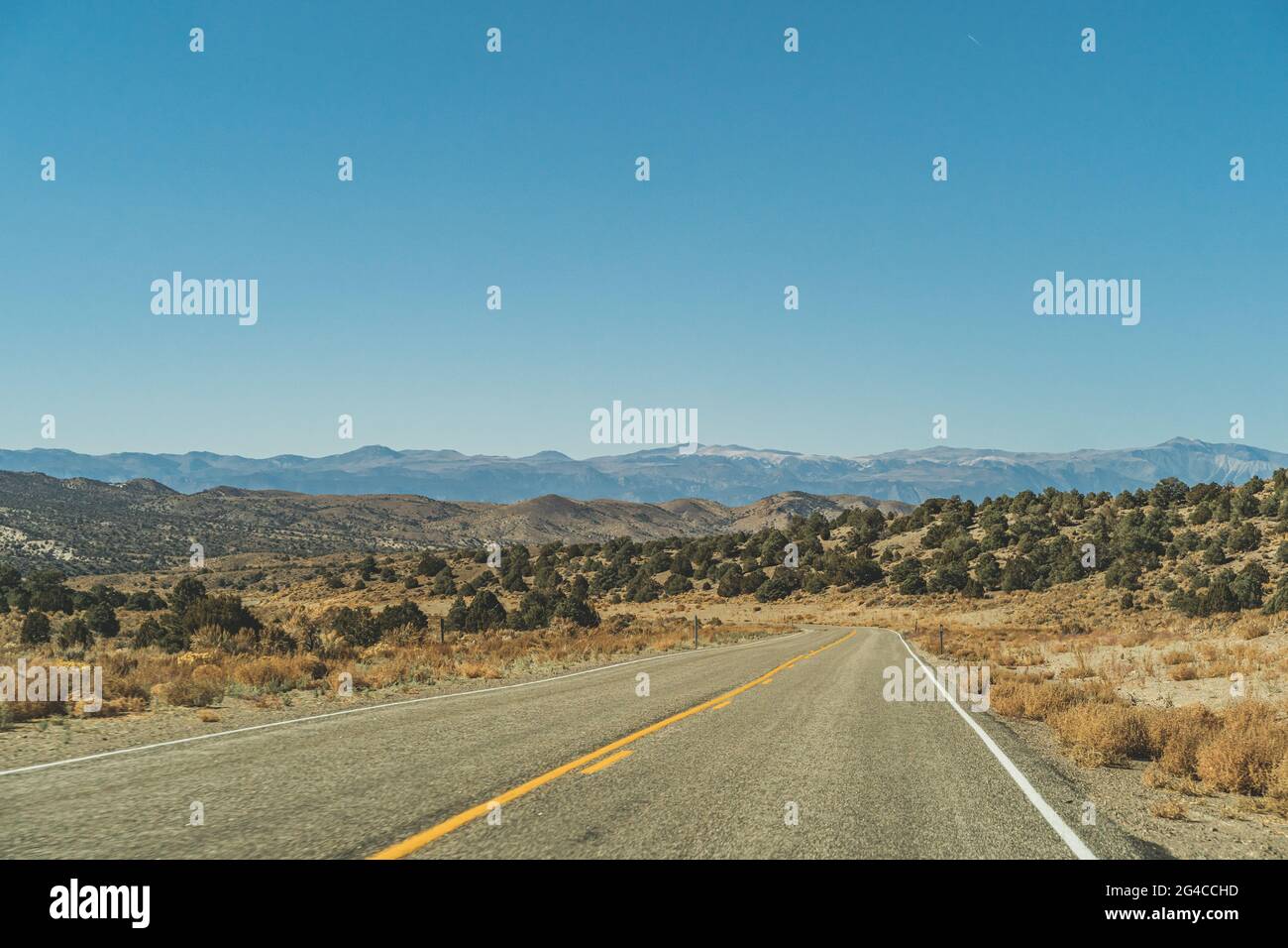 Strada a due corsie nella arida Sierra Nevada che conduce a. montagne contro il cielo blu Foto Stock