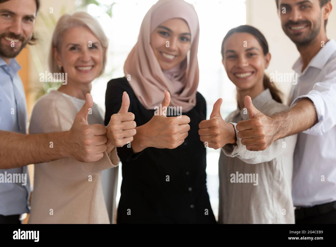 Il team dei dipendenti multietnici è felice di mostrare i pollici da vicino Foto Stock