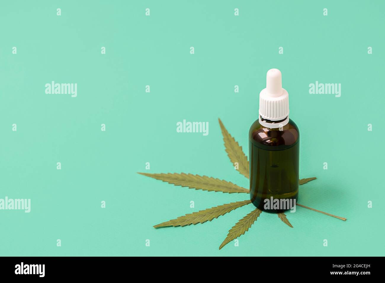 Olio di cannabis con foglie di cannabis su sfondo verde con spazio per il testo. Concetto di cannabis medica Foto Stock