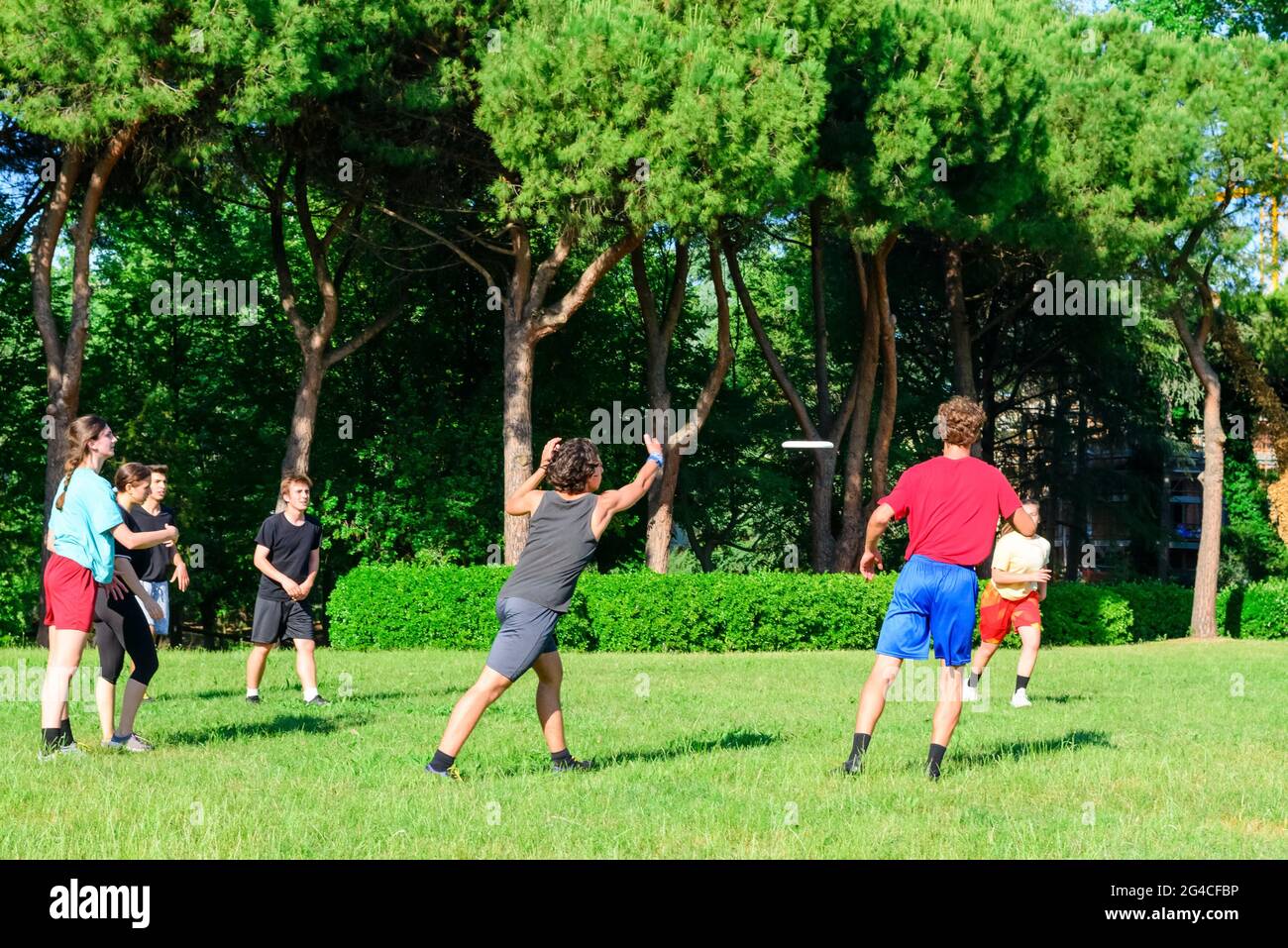 Gruppo di giovani adolescenti misti, persone in abbigliamento casual che giocano con un gioco su disco di plastica volante in un parco oudoors. Uomini e donne lancia un disco in una squadra Foto Stock