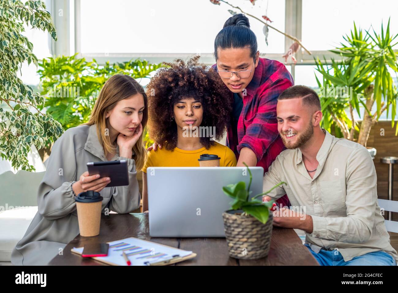 gruppo di giovani adulti che discutono di un serio progetto di start up nello spazio di cooworking indoor. diversi studenti che lavorano insieme su laptop e tablet al lavoro Foto Stock