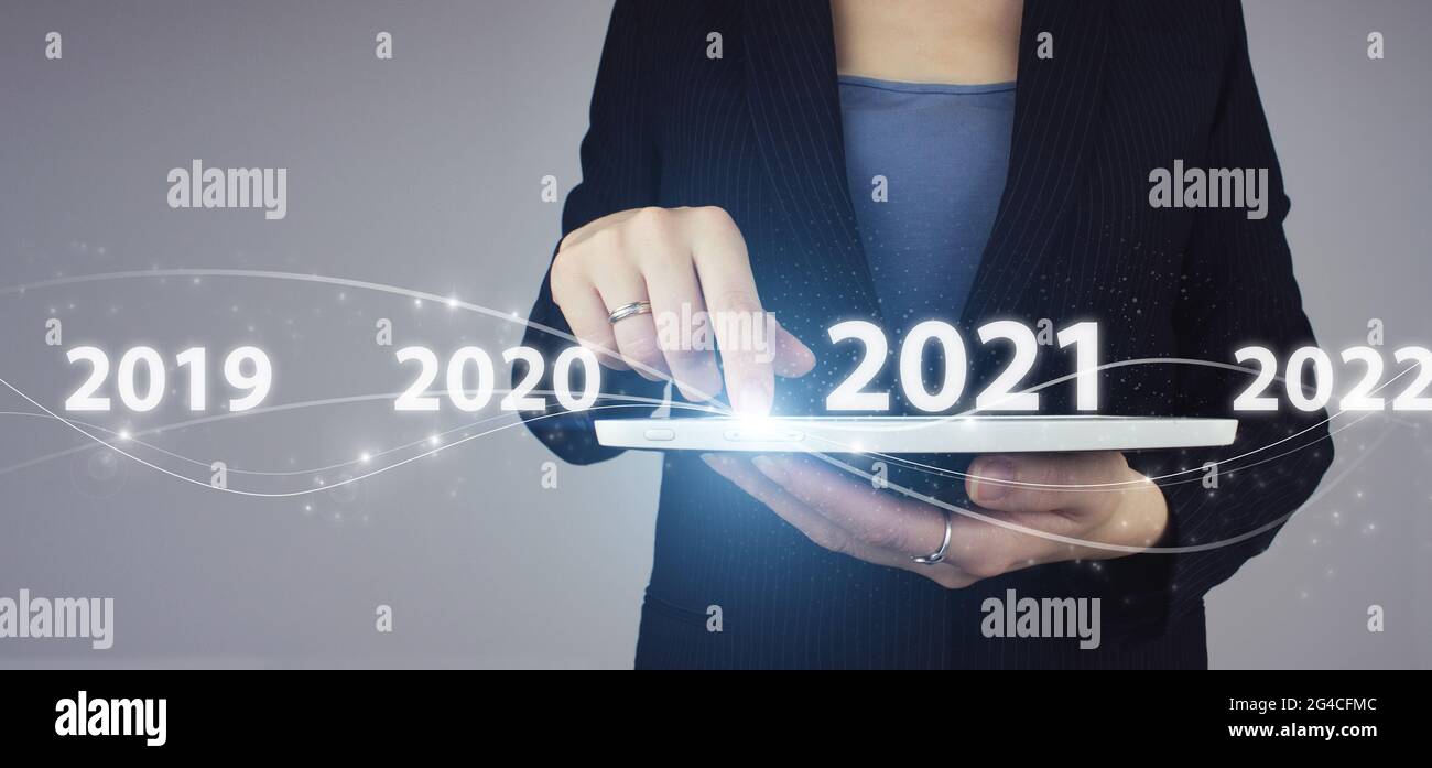 Concetto di carta di nuovo anno aziendale. Tablet bianco in mano donna d'affari con ologramma digitale 2021 anni segno su sfondo grigio Foto Stock