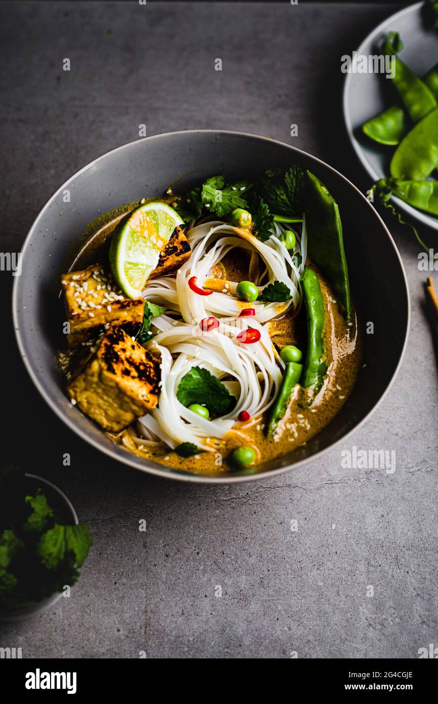 Zuppa di noodle Laska a base di piante con tofu, piselli dolci, coriandolo e peperoncino Singapore, malese. Semplice ricetta sana Foto Stock