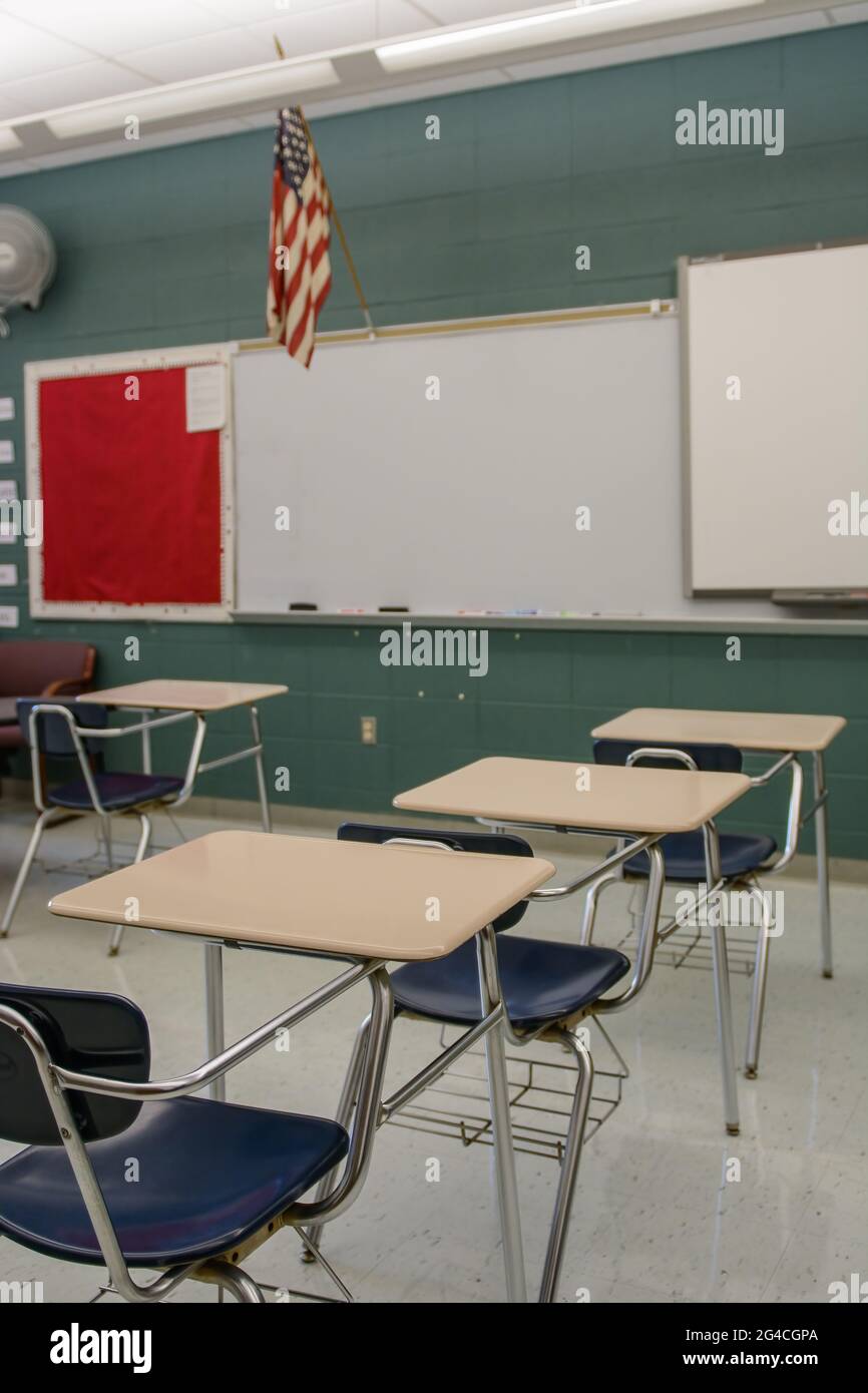 Classe con scrivanie, sedie, una bandiera e una lavagna bianca. Foto Stock