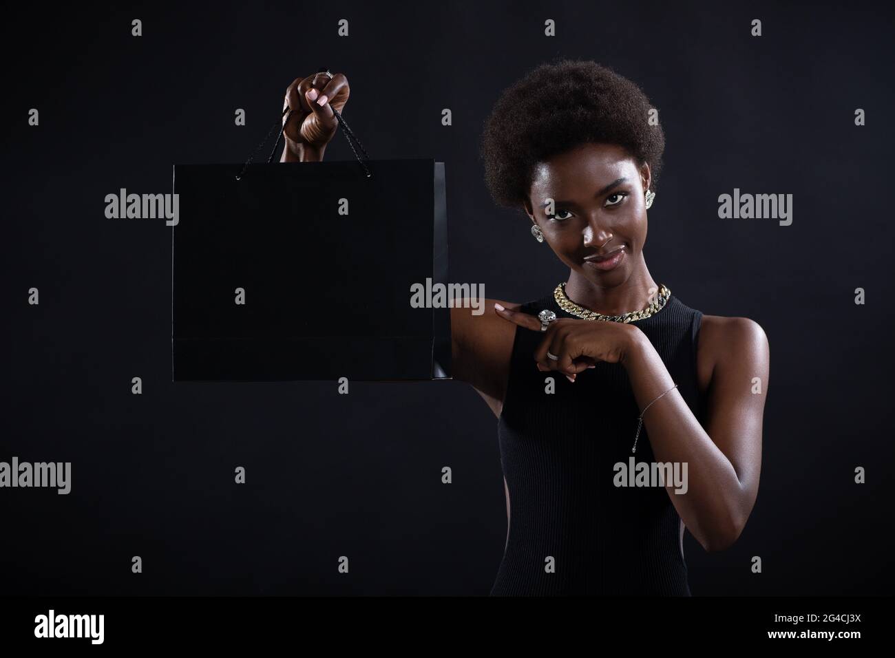 Donna afroamericana con acconciatura afro puntando dito nero borse della spesa. Vendita e Black Friday Concept. Foto Stock