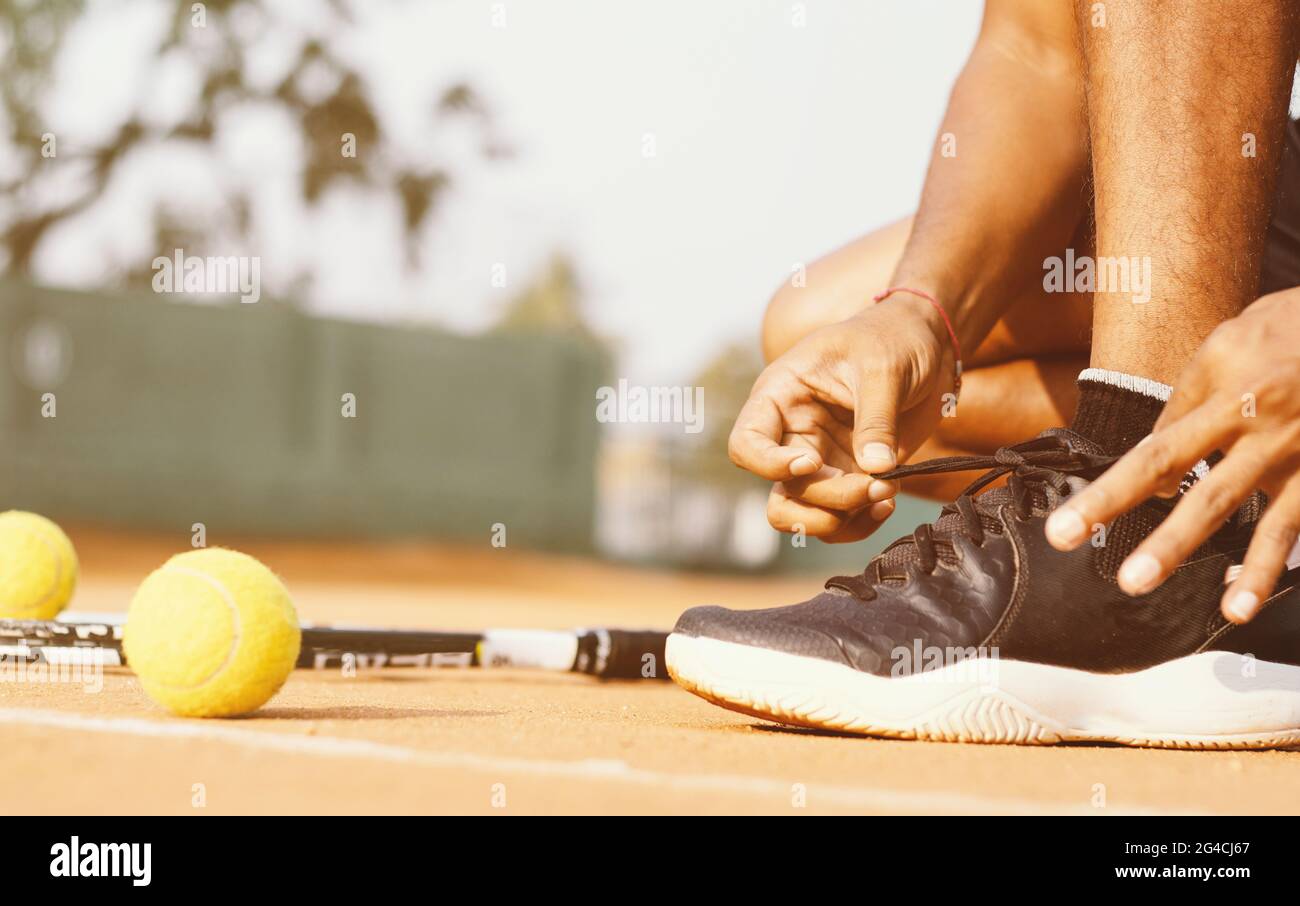 Un primo piano di un atleta maschile che lega le sue scarpe al campo da  tennis Foto stock - Alamy