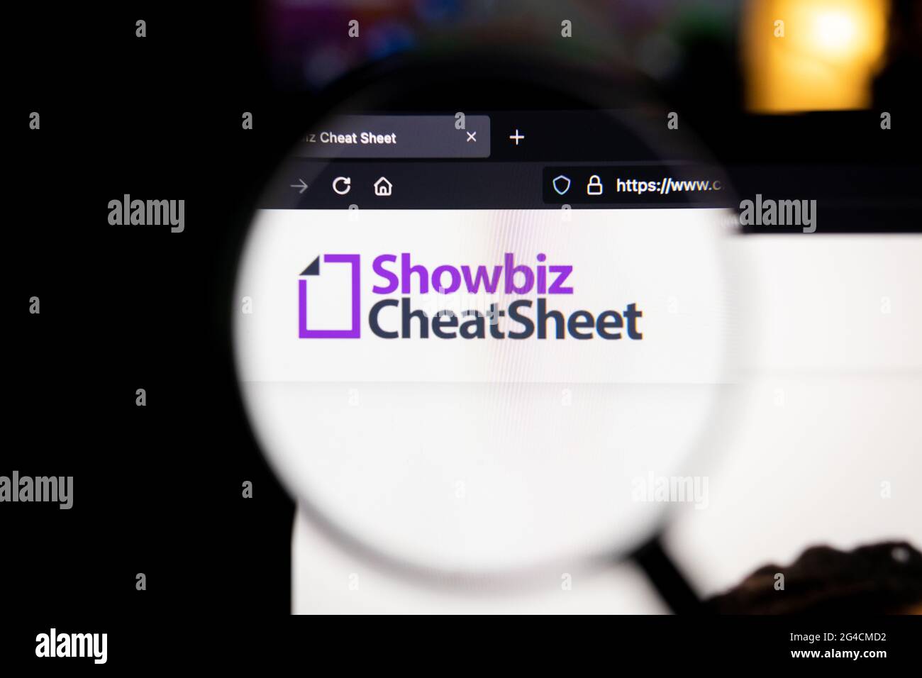 Showbiz cheatsheet Company logo su un sito web, visto su uno schermo del computer attraverso una lente di ingrandimento. Foto Stock