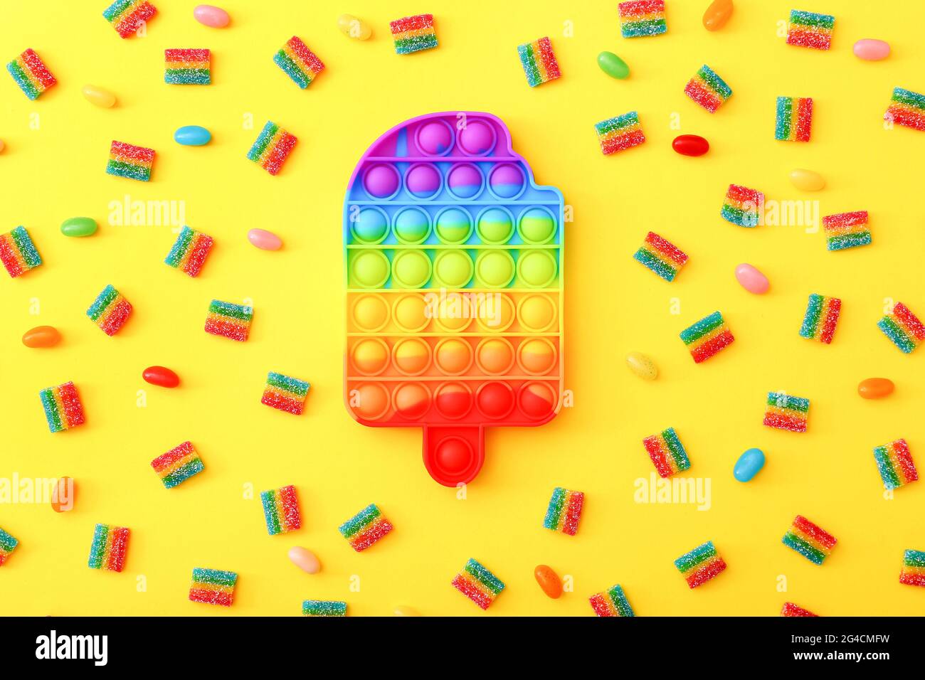 Rainbow Pop è un gioco di fidget accanto alle colorate caramelle di marmellata su sfondo giallo. Foto Stock