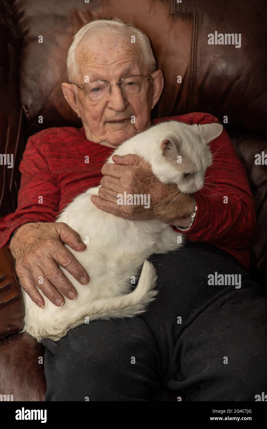 Anziano uomo di 97 anni che tiene il suo gatto bianco, Buddy. Foto Stock