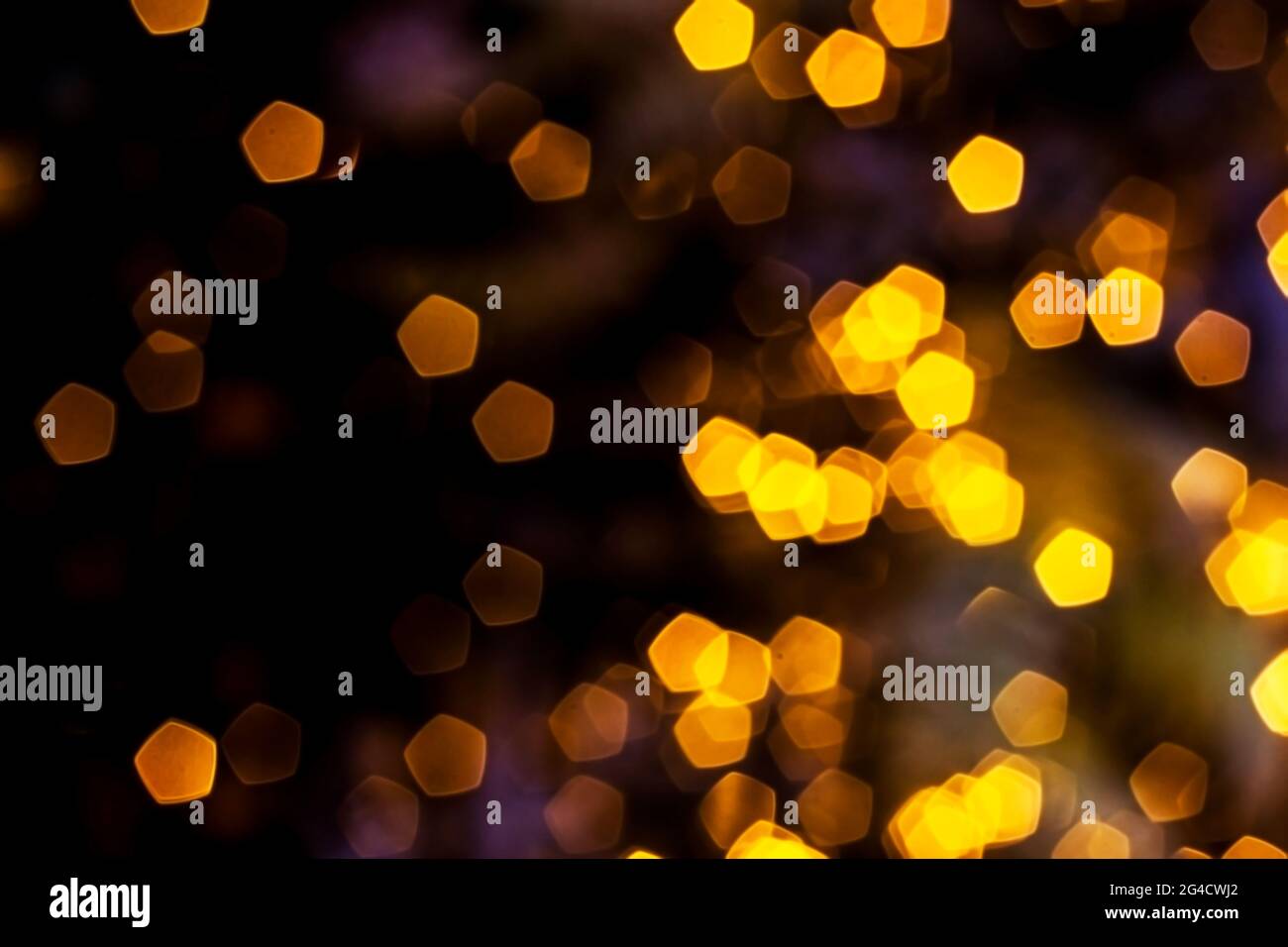 Luci dorate offuscate sfondo astratto di notte, sfocato sfondo bokeh scuro e luminoso, magico motivo giallo illuminato brillante. Foto Stock