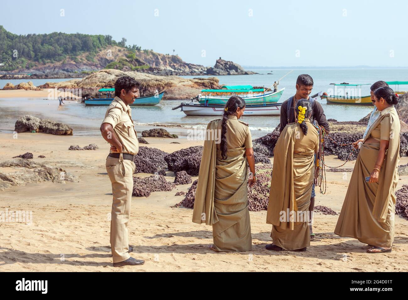 Ufficiali di polizia indiani femminili in uniformi di kaki che controllano le collane di un falchiere di spiaggia, Om Beach, Gokarna, Karnataka, India Foto Stock