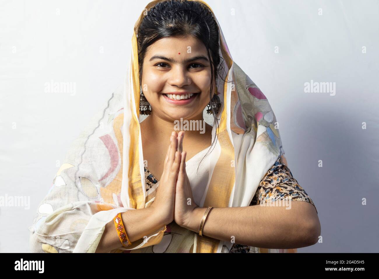 Una bella donna indiana in saree isolate su sfondo bianco accoglie in posa namaste con volto sorridente Foto Stock