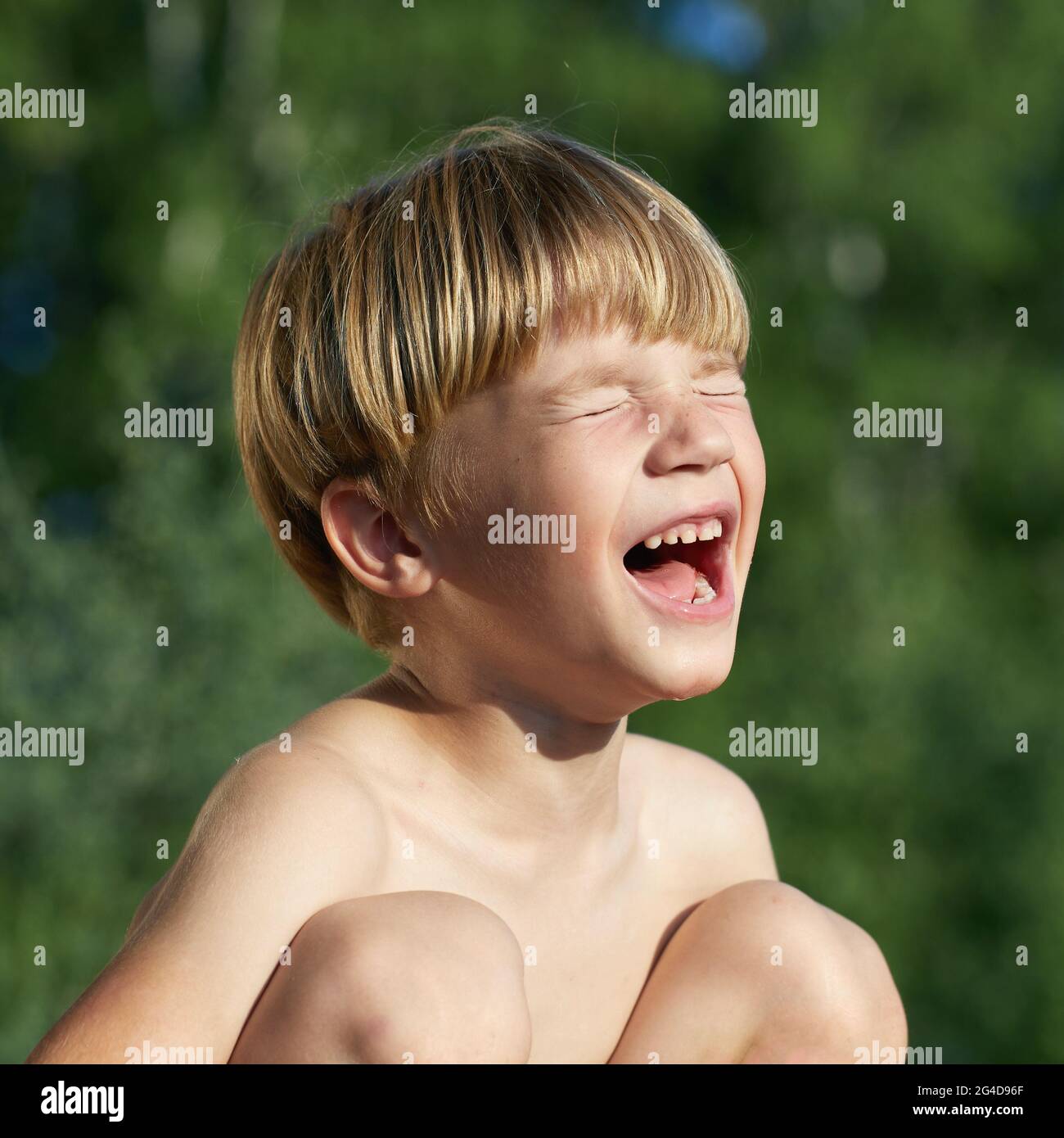 ritratto di piccolo ragazzo arrabbiato urlando e urlando con eyea chiusa su sfondo verde naturale, all'aperto Foto Stock