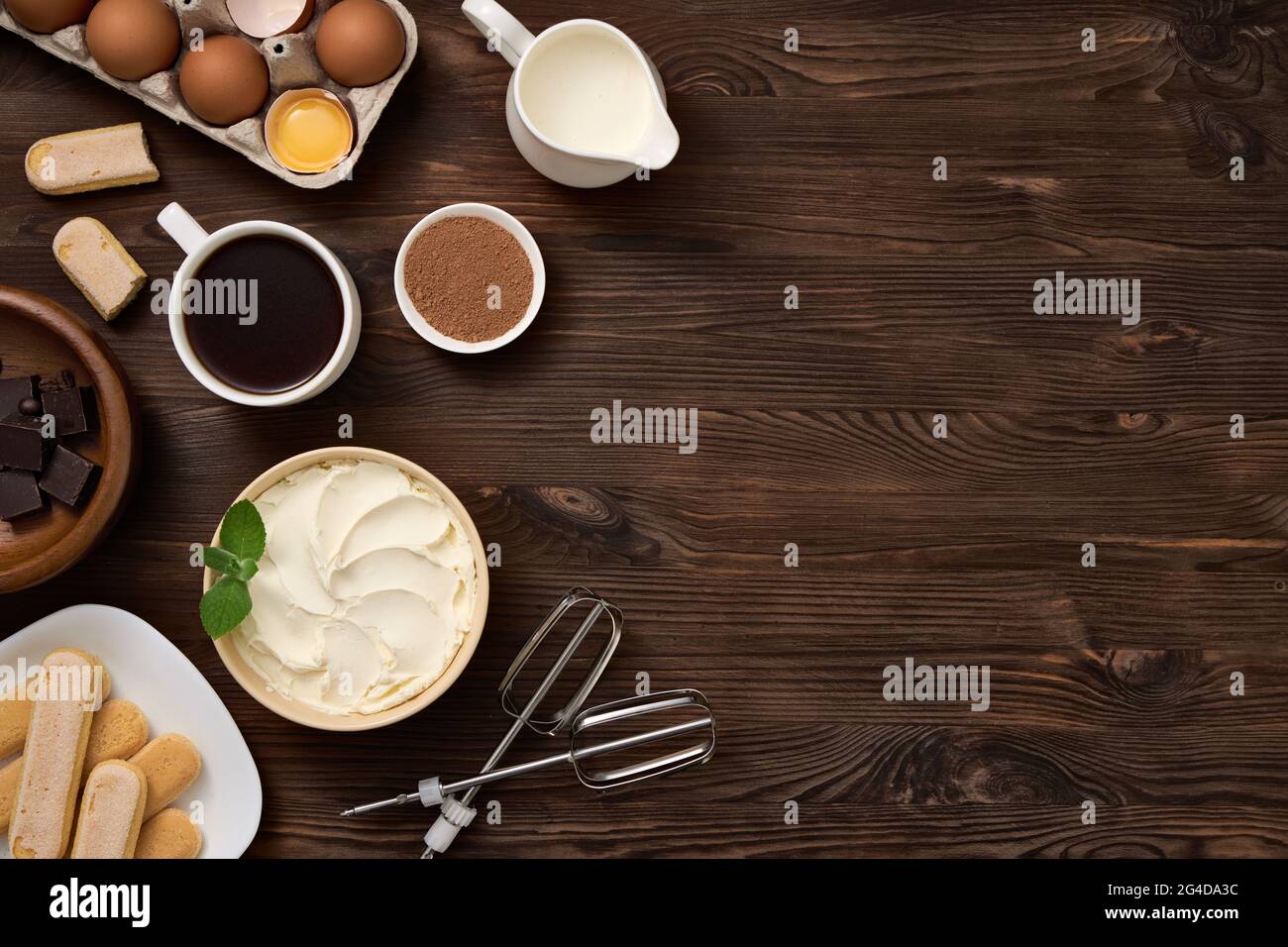 Prodotto per la preparazione di dessert tiramisù. Vista dall'alto degli ingredienti sulla tavola di legno marrone scuro. Spazio libero per un'iscrizione. Foto Stock
