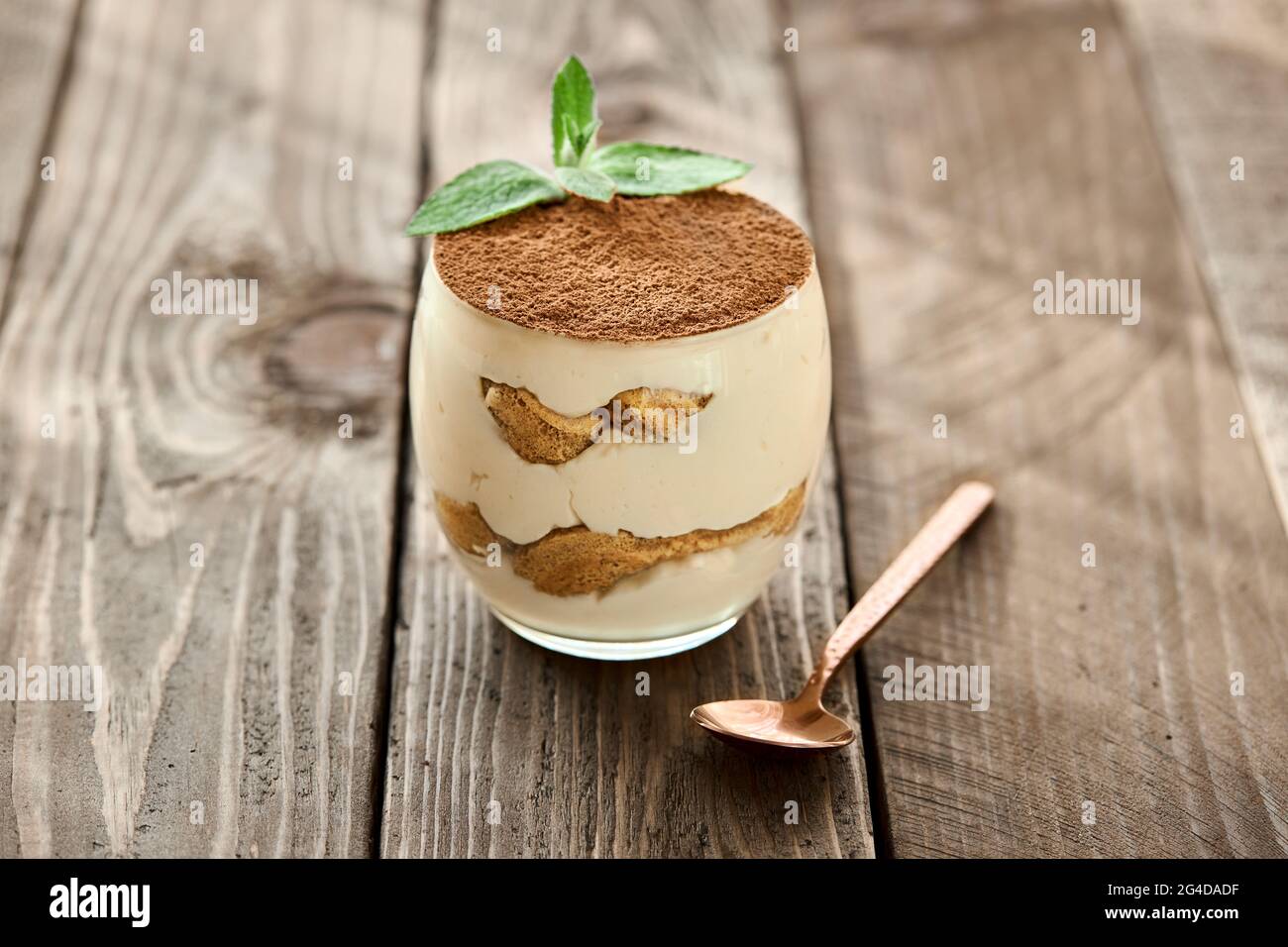 Dessert classico Tiramisu in un bicchiere su una tavola di legno in una giornata di sole. Foto Stock