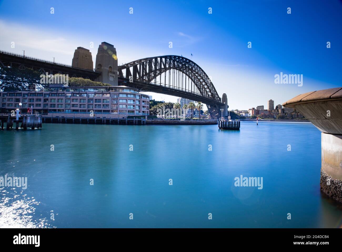 Lunga esposizione Sydney Harbour Australia in una giornata soleggiata cielo azzurro con i colori turchesi della baia. Teatro dell'opera e edifici di Harbour Bridge Foto Stock