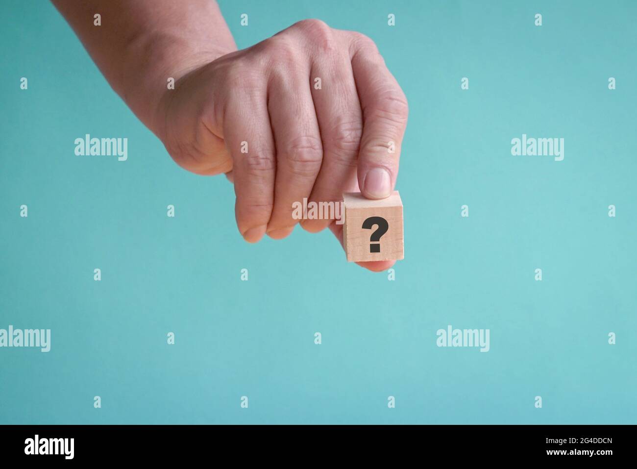 Tenendo a mano un pezzo di blocco di legno vuoto con punto interrogativo. Spazio di copia. Foto Stock
