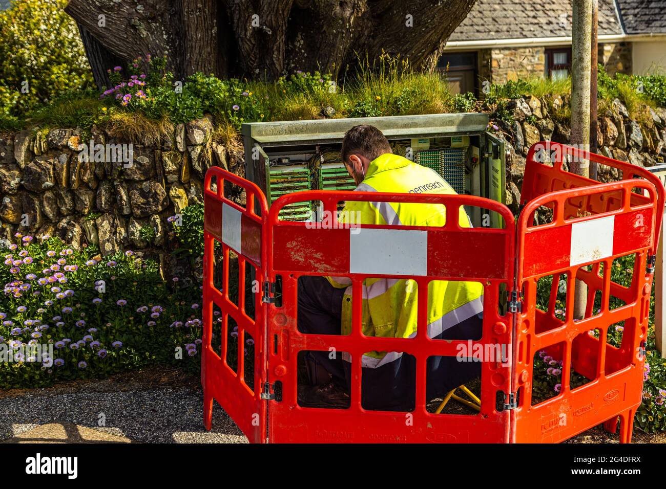 Un ingegnere delle telecomunicazioni lavora per risolvere i problemi di connessione in un armadio di strada, Cornwall Inghilterra UK Foto Stock