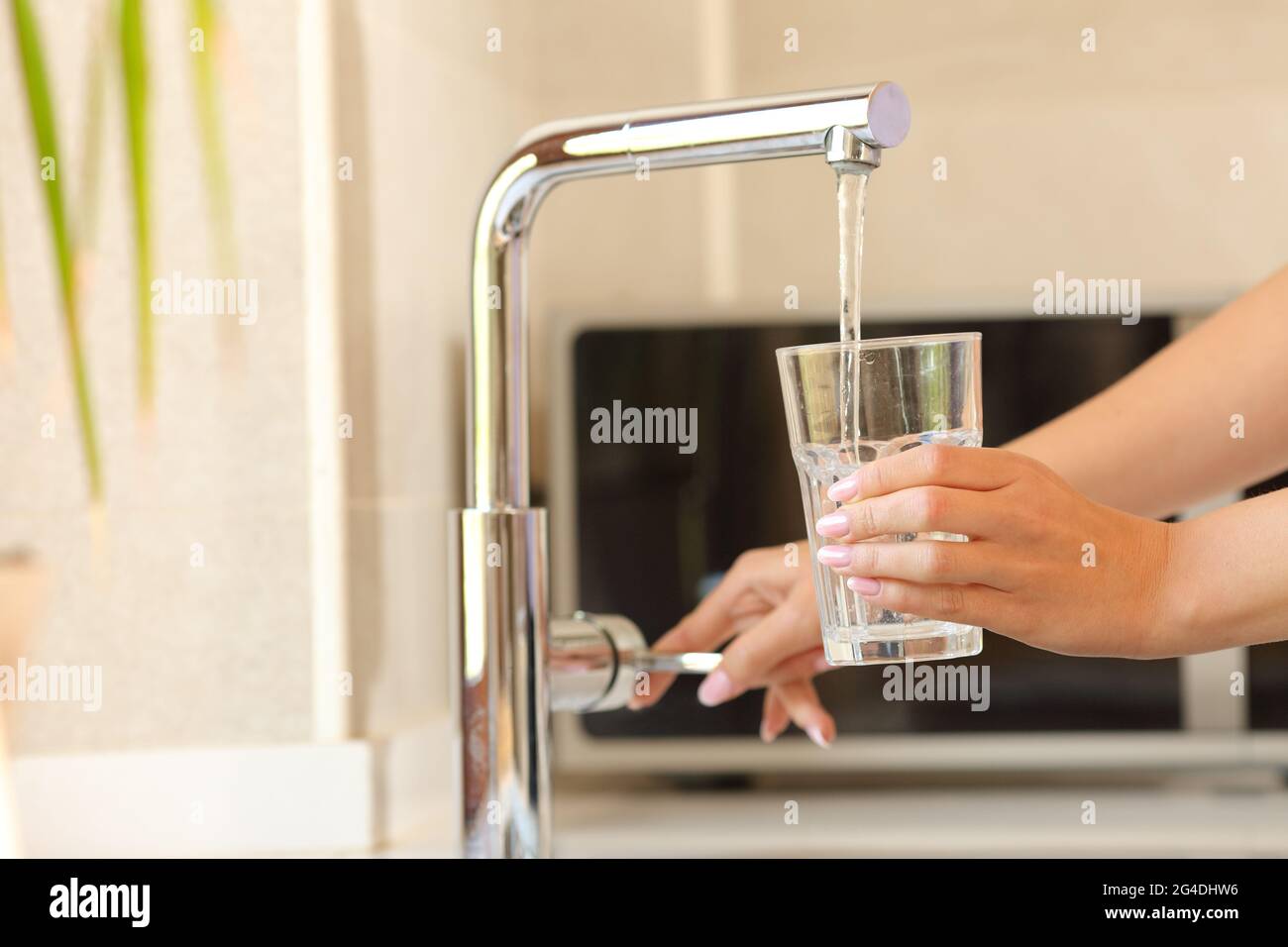 Primo piano di una donna che riempie un bicchiere d'acqua del rubinetto Foto Stock