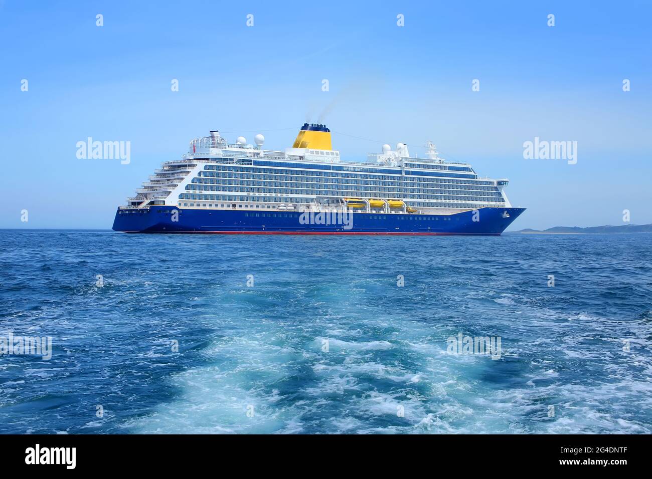 Nave da crociera all'ancora sul porto di San Pietro, Guernsey. Grande nave con scafo blu e imbuto giallo al largo della costa delle Isole della Manica, Regno Unito. Foto Stock