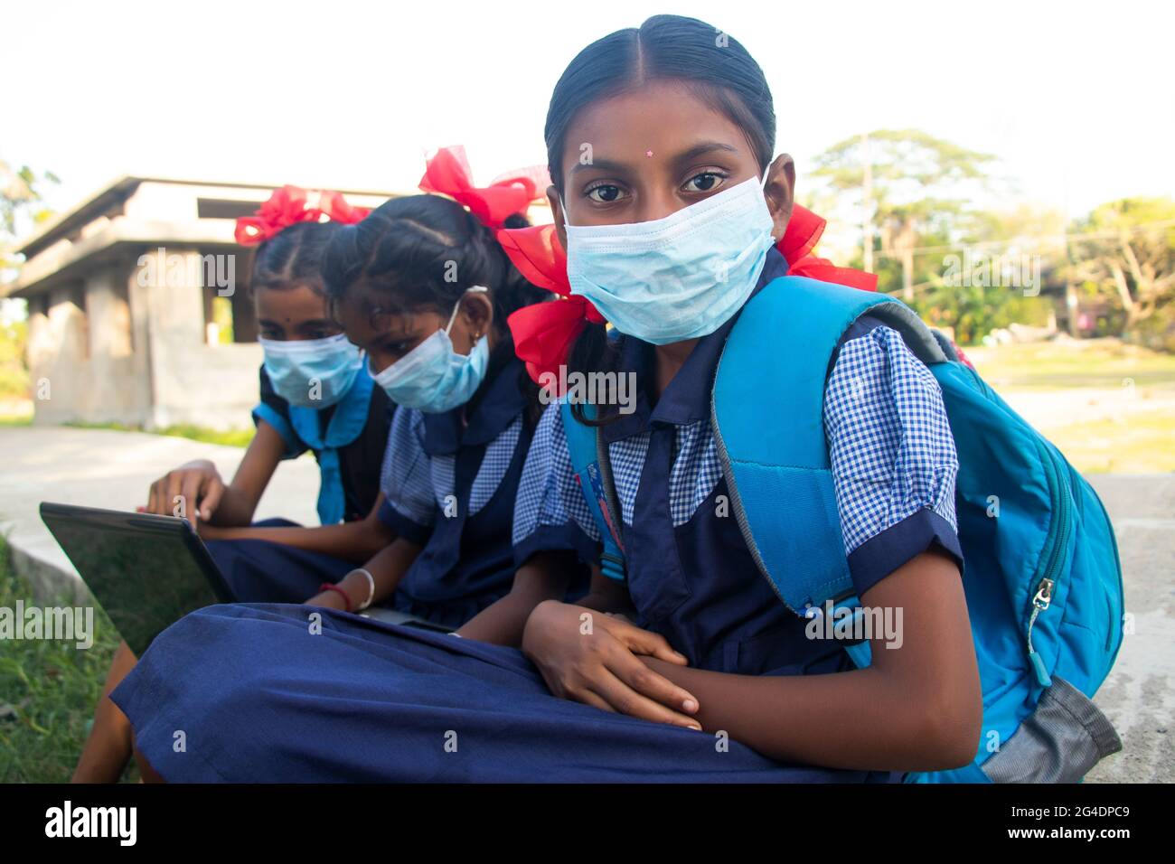 le ragazze della scuola di governo del villaggio indiano indossano la maschera usando il laptop Foto Stock