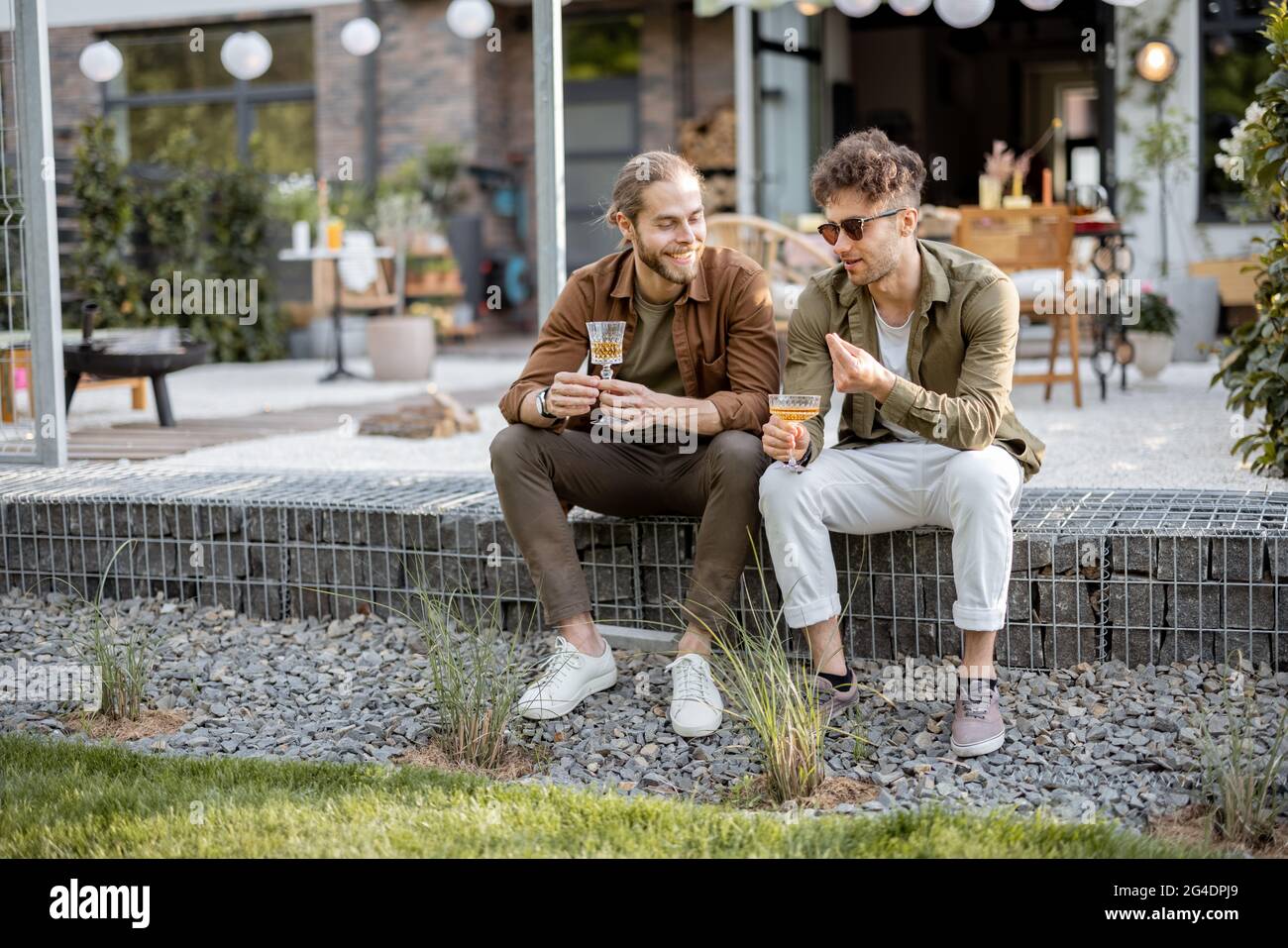 Due amici maschi che parlano su un portico della casa di campagna Foto Stock