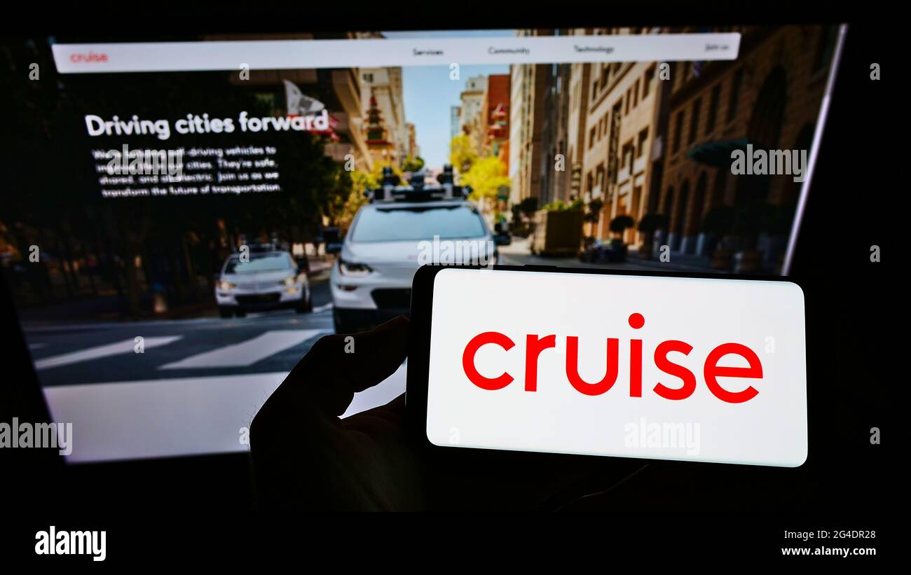 Persona che detiene smartphone con il logo della società di auto a guida autonoma degli Stati Uniti Cruise LLC sullo schermo di fronte al sito web. Mettere a fuoco il display del telefono. Foto Stock