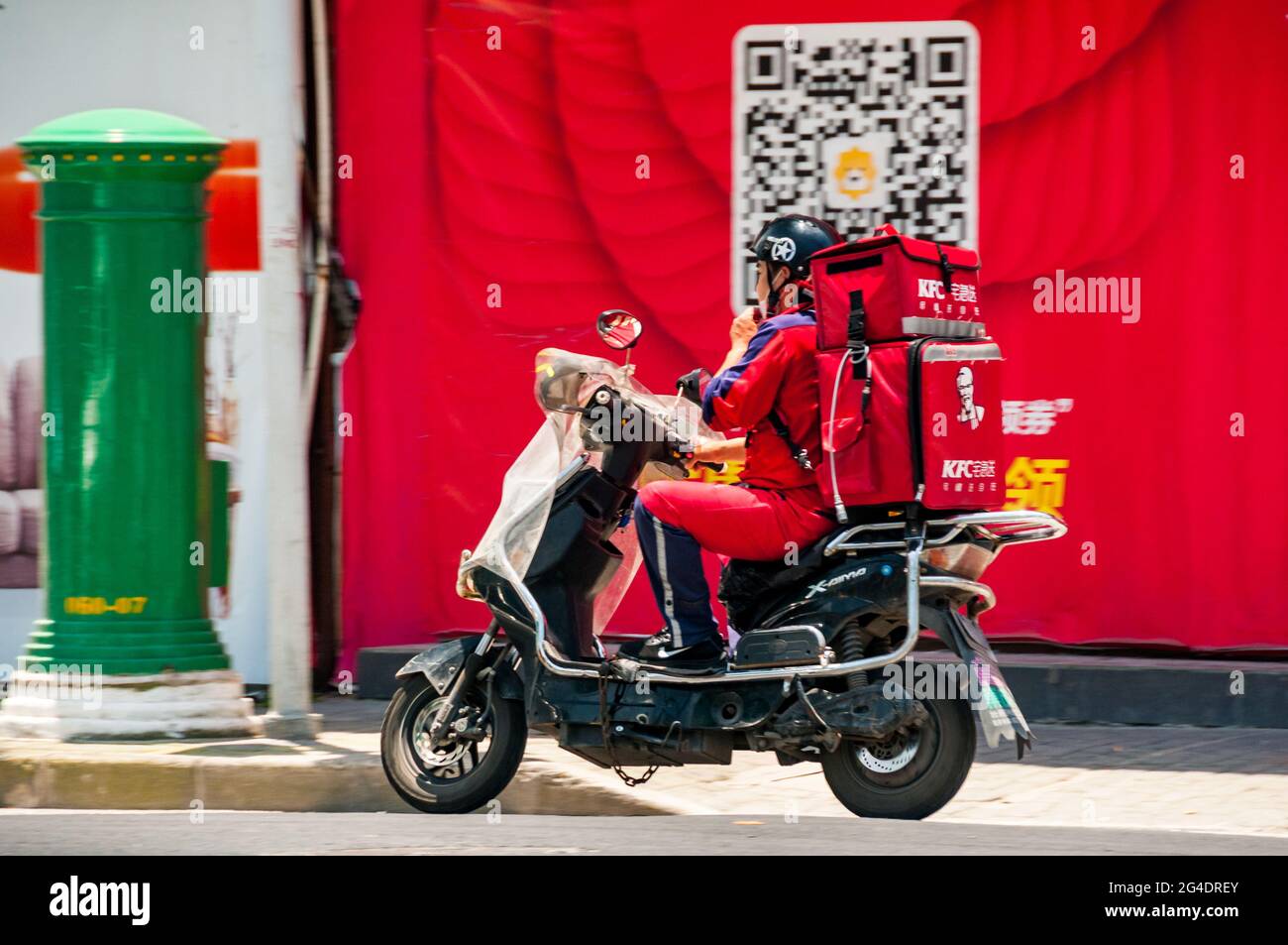 Un pilota con consegna KFC su uno scooter all'incrocio tra le strade di Aomen e Changhua vicino all'area artistica M50 nel distretto di Putuo, Shanghai, Cina. Foto Stock