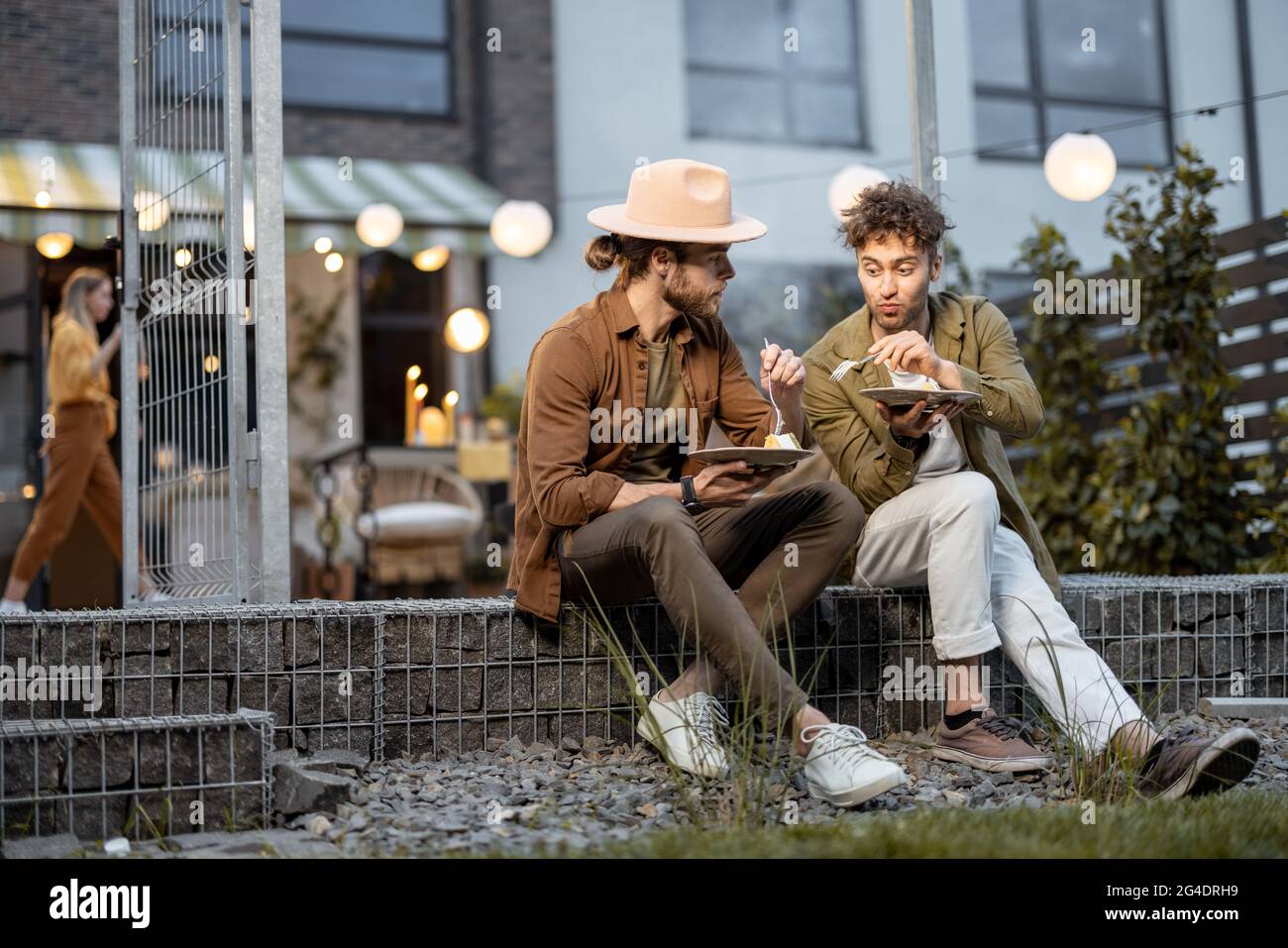 Due amici maschi che parlano su un portico della casa di campagna Foto Stock