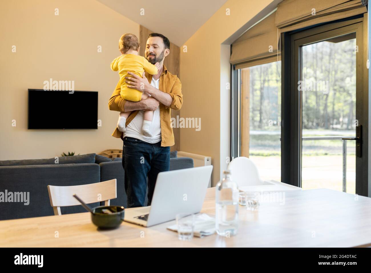 Padre che allatta il suo figlio e lavora da casa Foto Stock