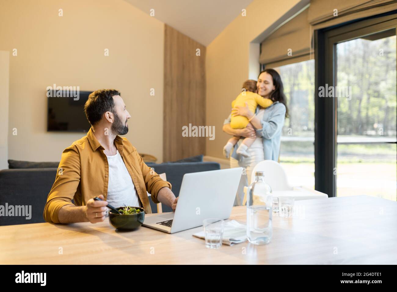 Padre lavora da casa con la sua famiglia Foto Stock
