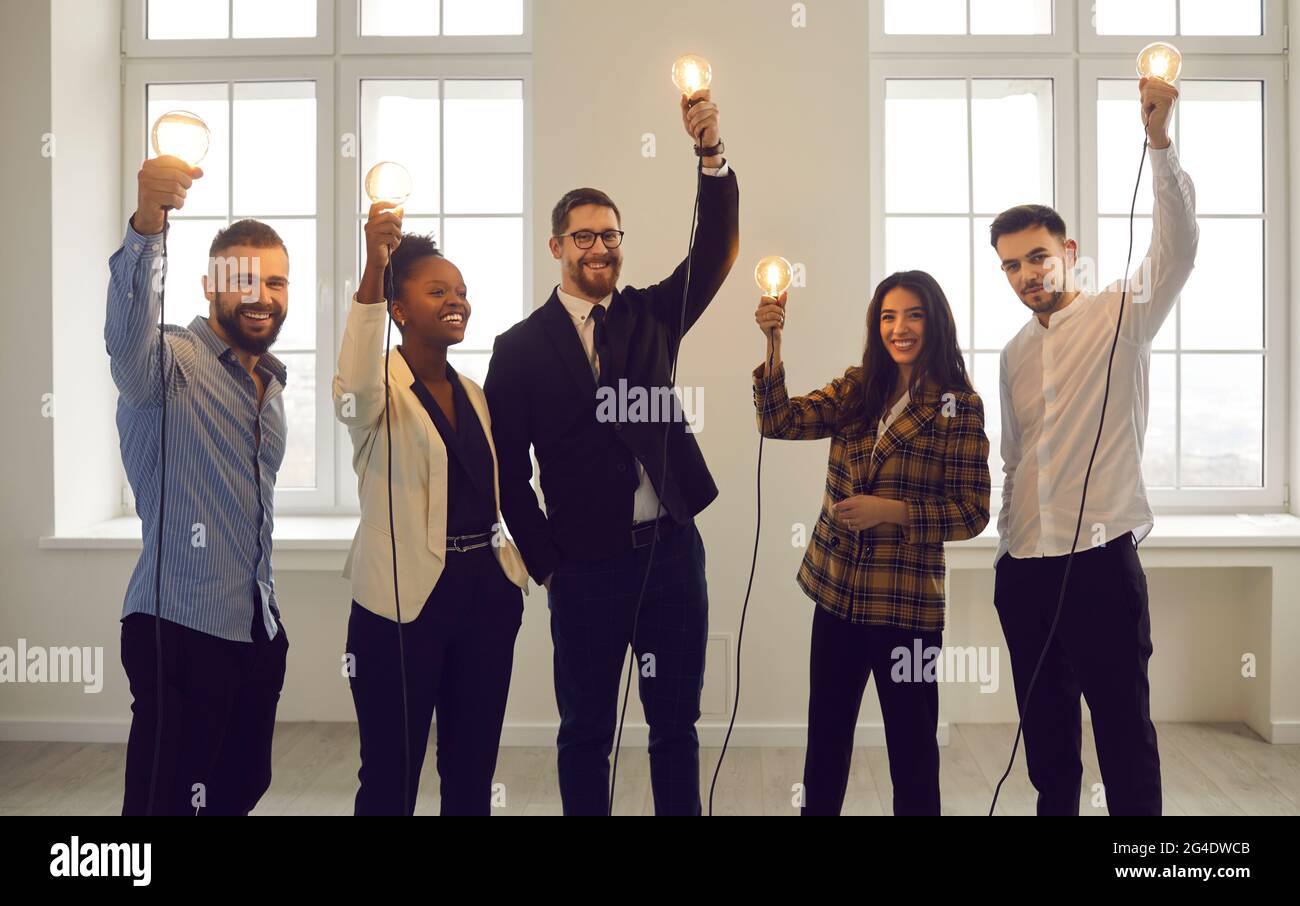 Team di uomini d'affari internazionali si leva con lampade rialzate che simboleggiano l'idea. Foto Stock