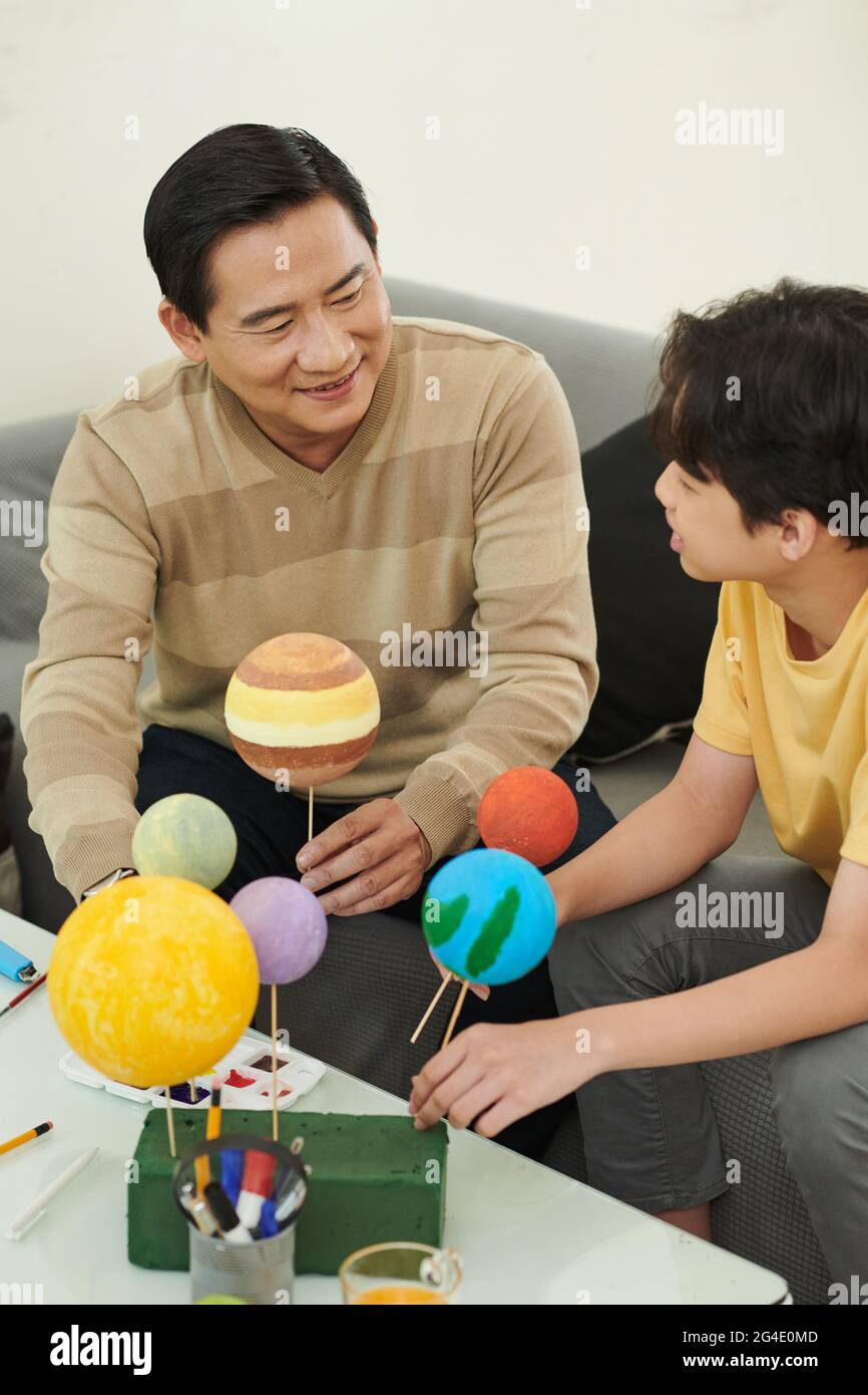 Padre e figlio si divertono a passare il tempo insieme e a fare il modello del sistema solare per la scuola Foto Stock