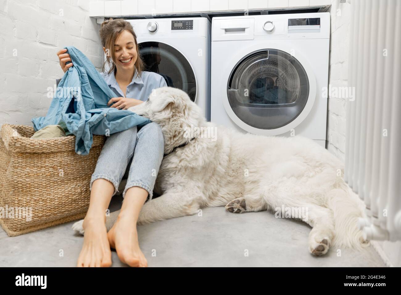 Donna con un cane che fa lavoro domestico nella lavanderia Foto Stock