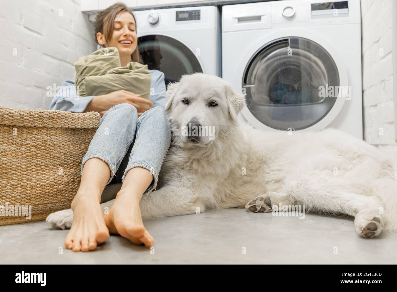 Donna con un cane che fa lavoro domestico nella lavanderia Foto Stock