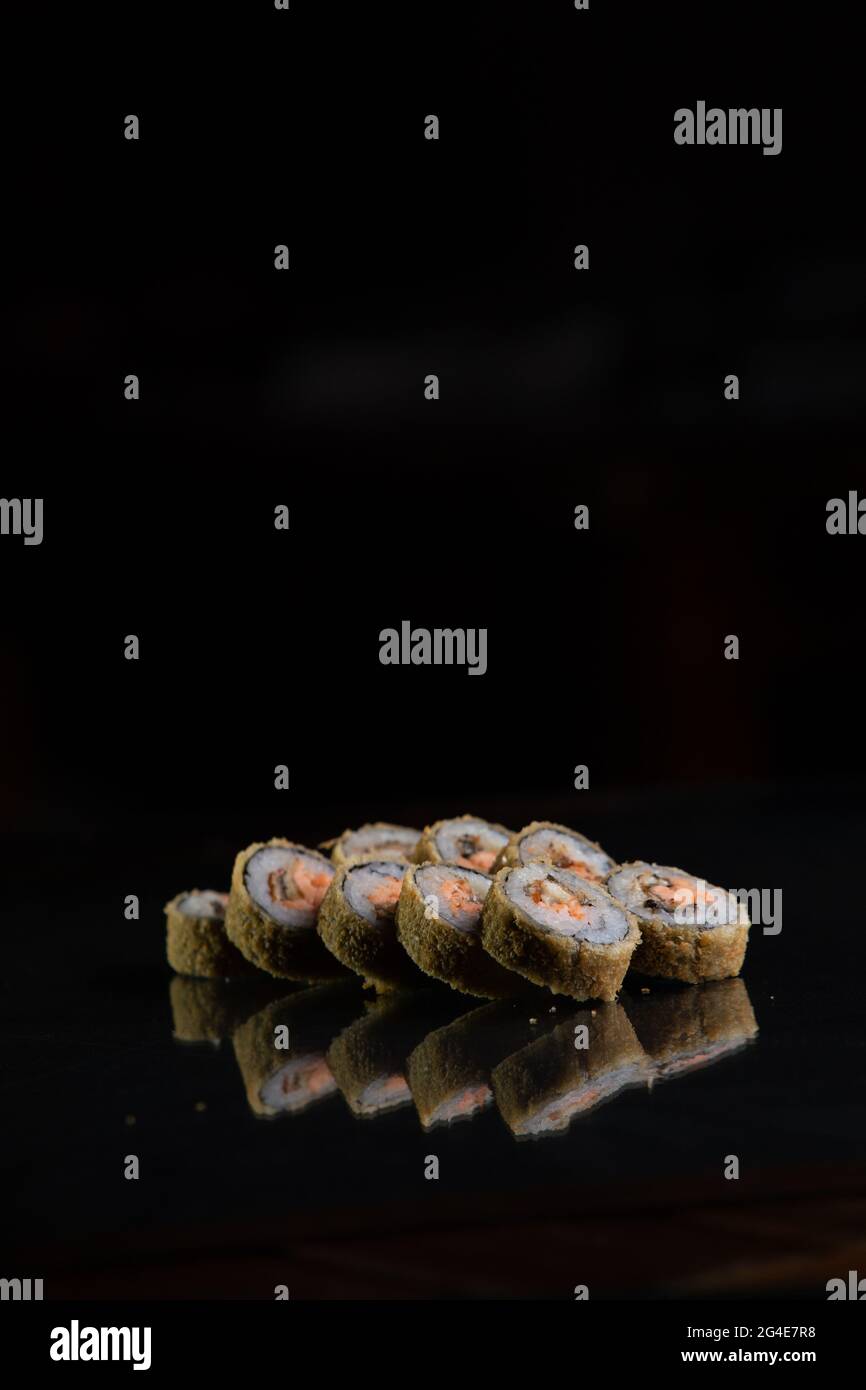 cucina giapponese. panini al sushi cotti su sfondo nero con riflessi. Foto Stock