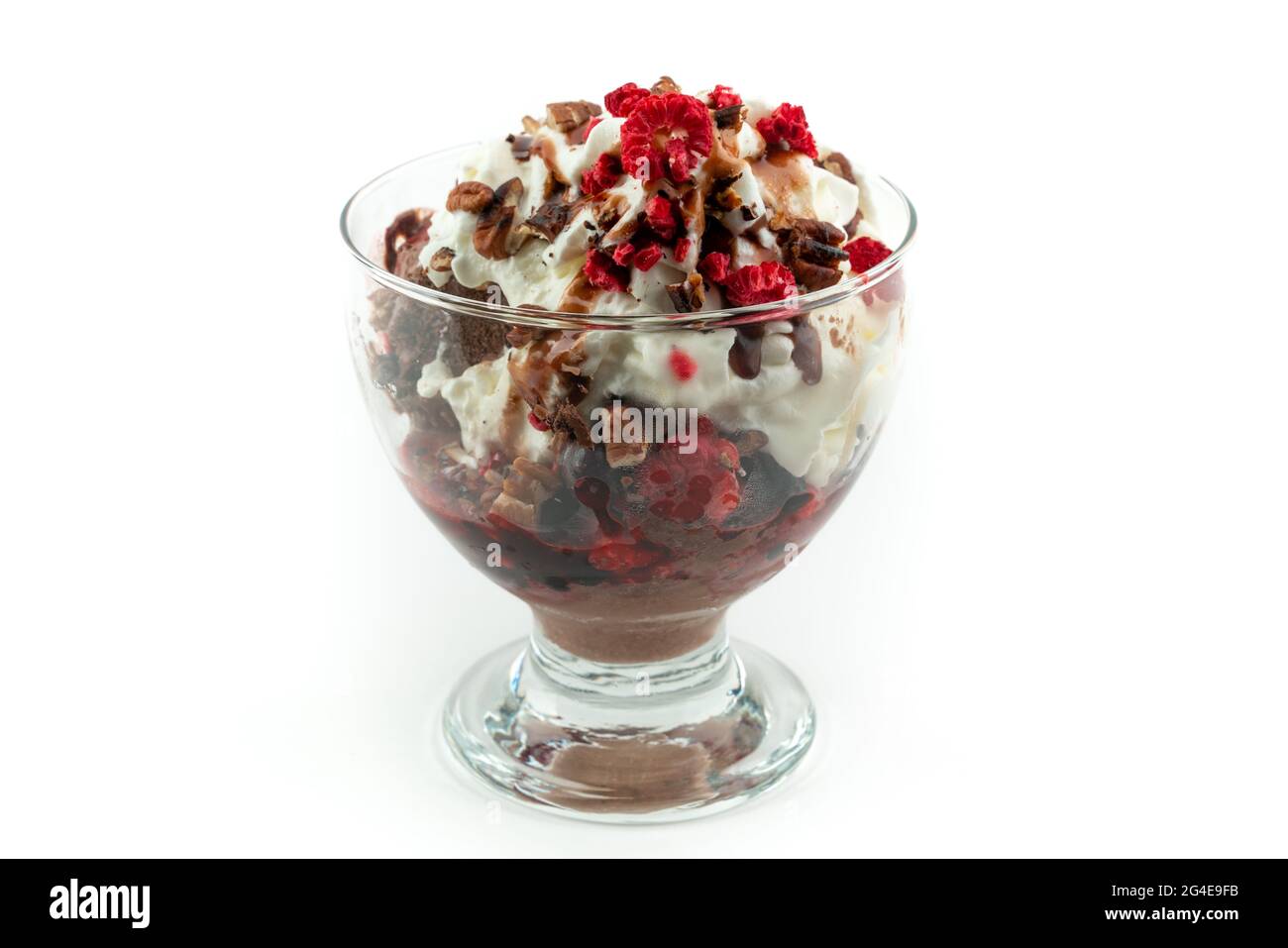 Gelato al cioccolato con panna, noci varie e bacche surgelate sopra, in una tazza di vetro, isolato su sfondo bianco Foto Stock