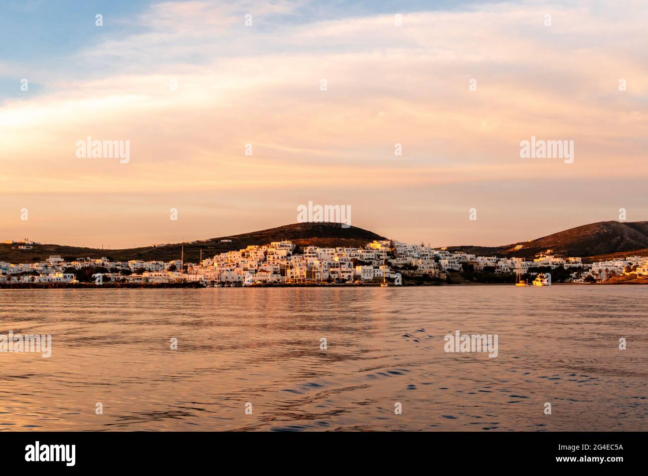 Villaggio costiero di Naoussa sull'isola di Paros con case bianche delle cicladi dai colori rosa dell'alba e dalle nuvole rosa nel cielo, al mattino presto in Grecia. Foto Stock