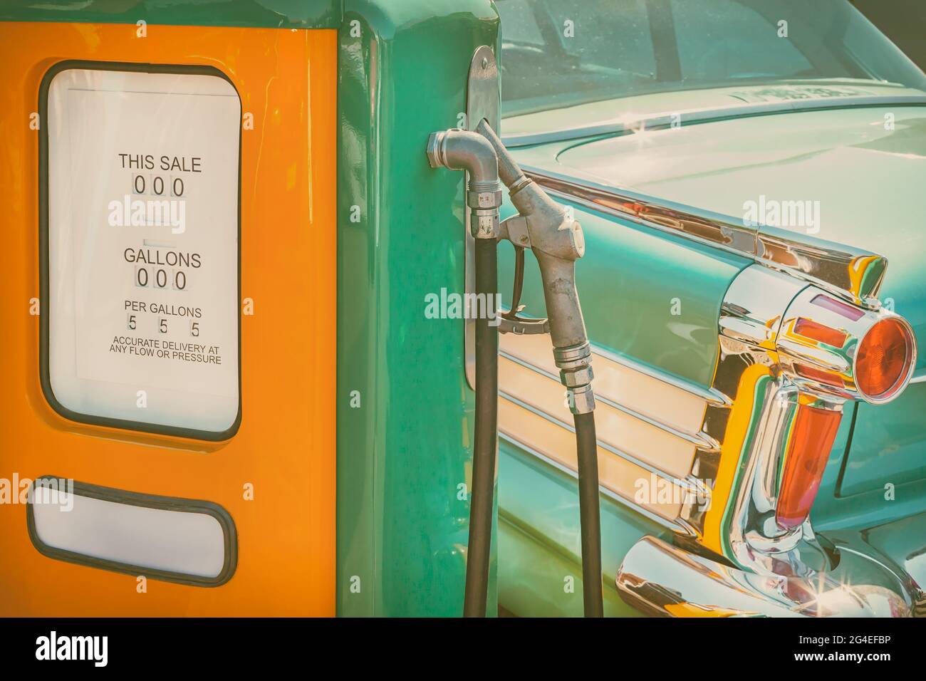 Immagine in stile retrò di una vecchia pompa di alimentazione e di un'auto verde classica Foto Stock