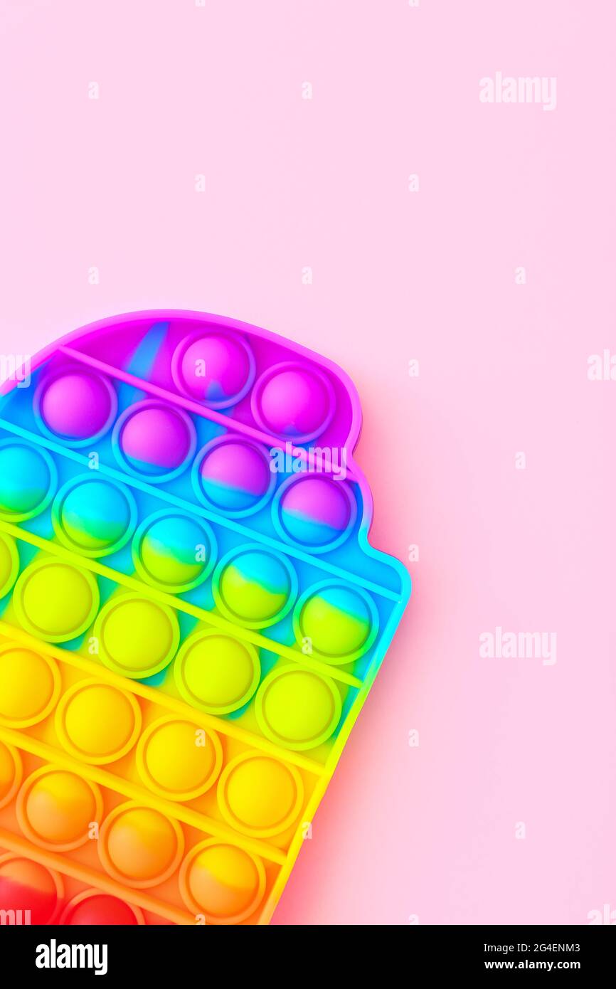 Colorful antistress sensoriale giocattolo fidget spingere pop esso su sfondo rosa, vista dall'alto Foto Stock