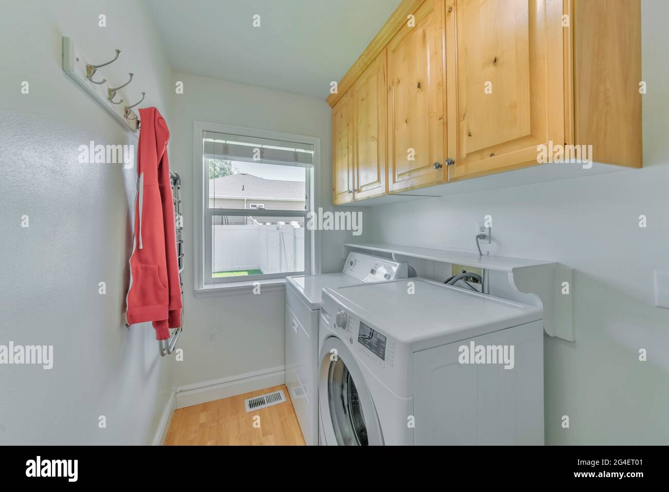 Una piccola lavanderia bianca con ripiani in legno, due lavatrici e una  finestra Foto stock - Alamy